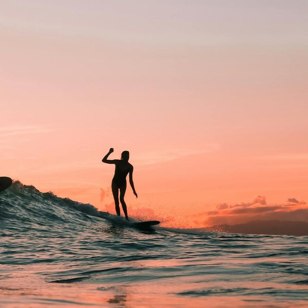Person feeling energetic and stretching outdoors at sunrise.